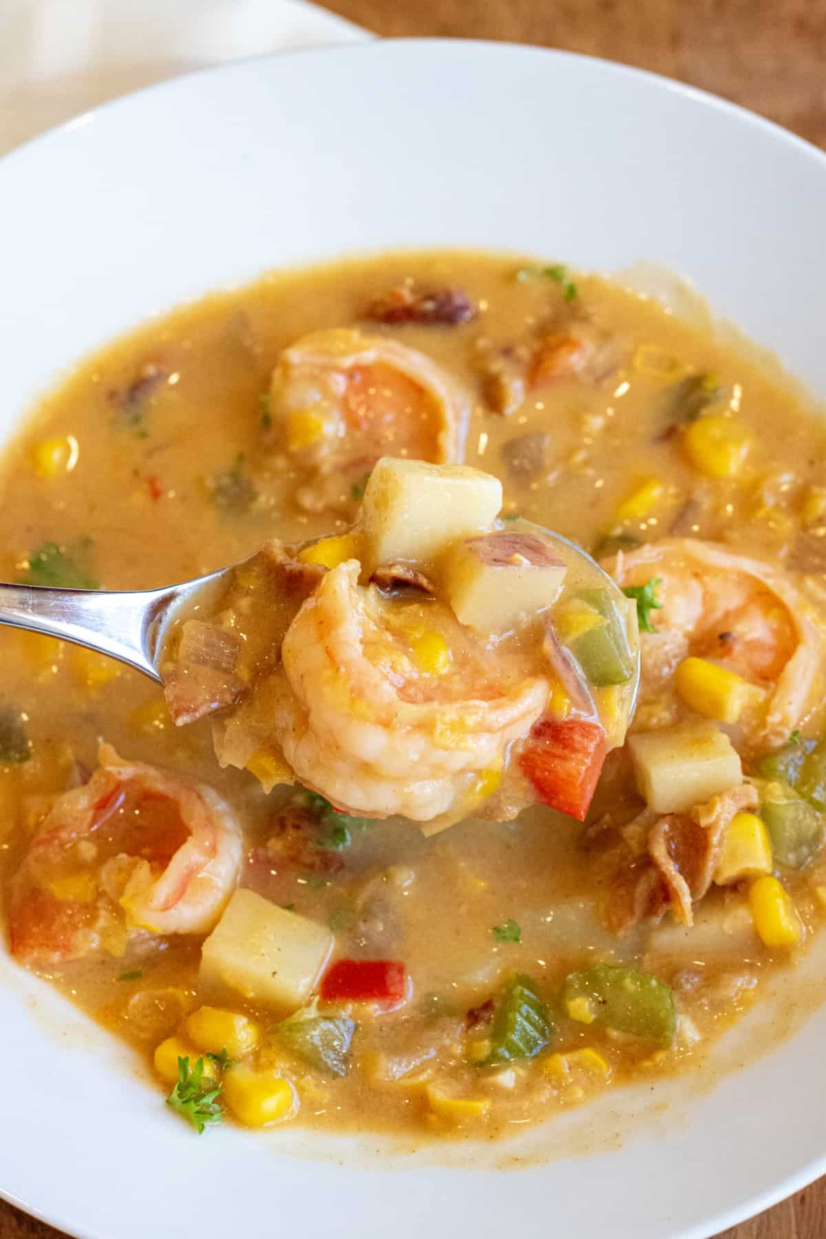 a bowl of shrimp corn chowder and a spoon holding up a spoonful.