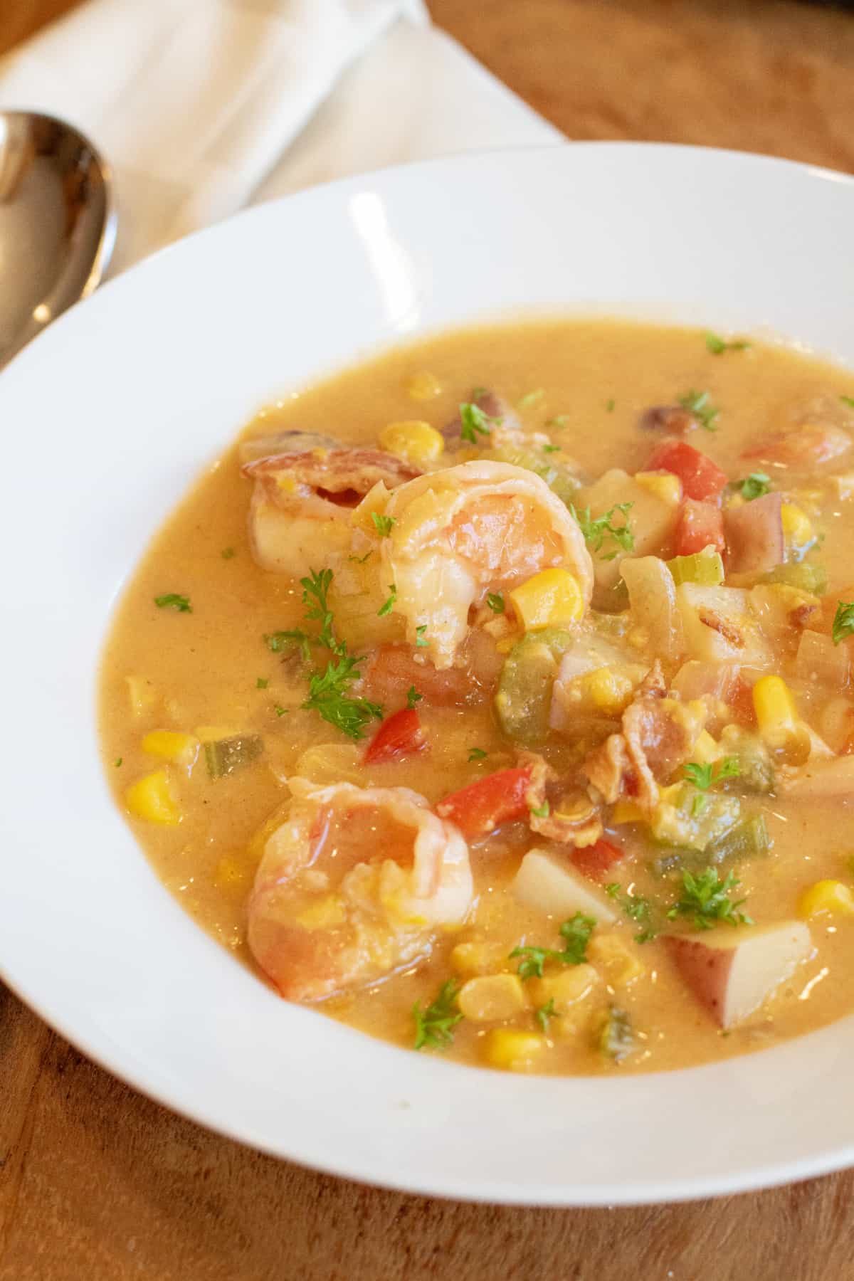 a bowl of shrimp chowder with corn red pepper and potatoes.