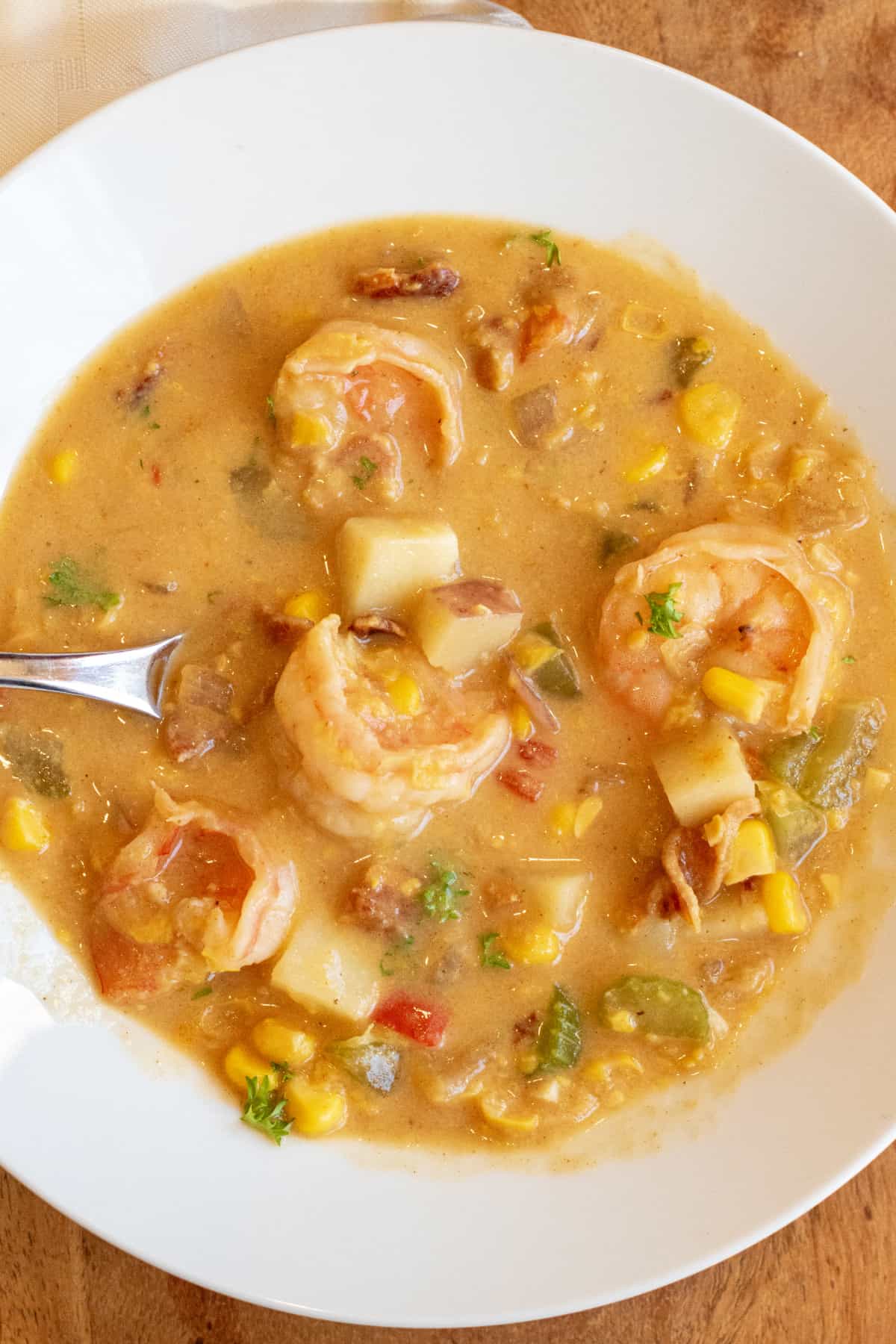 a bowl of shrimp chowder with corn red pepper and potatoes.
