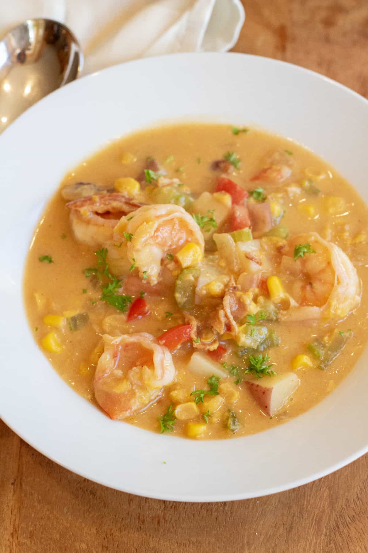 a bowl of shrimp chowder with corn red pepper and potatoes.
