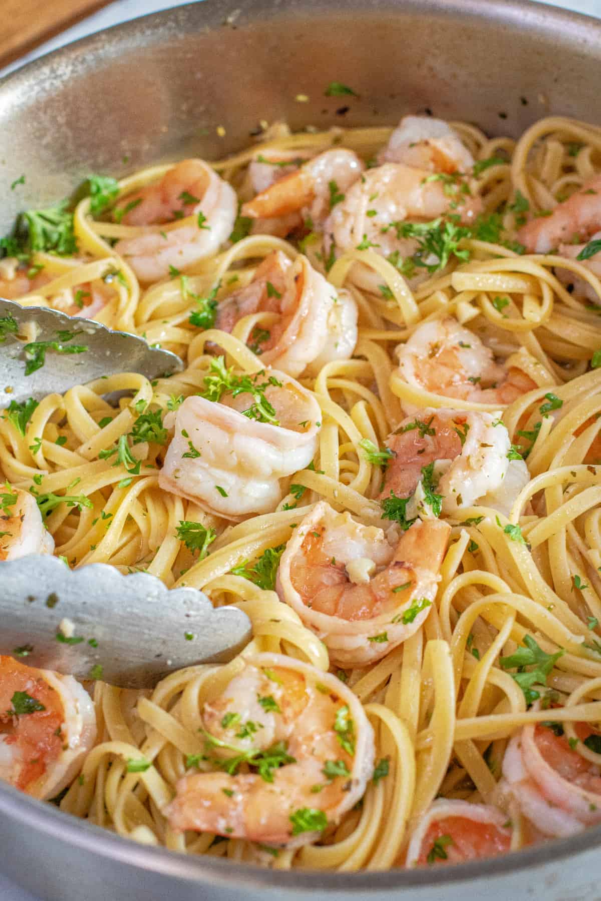 a pan of shrimp scampi with tongs in it. 