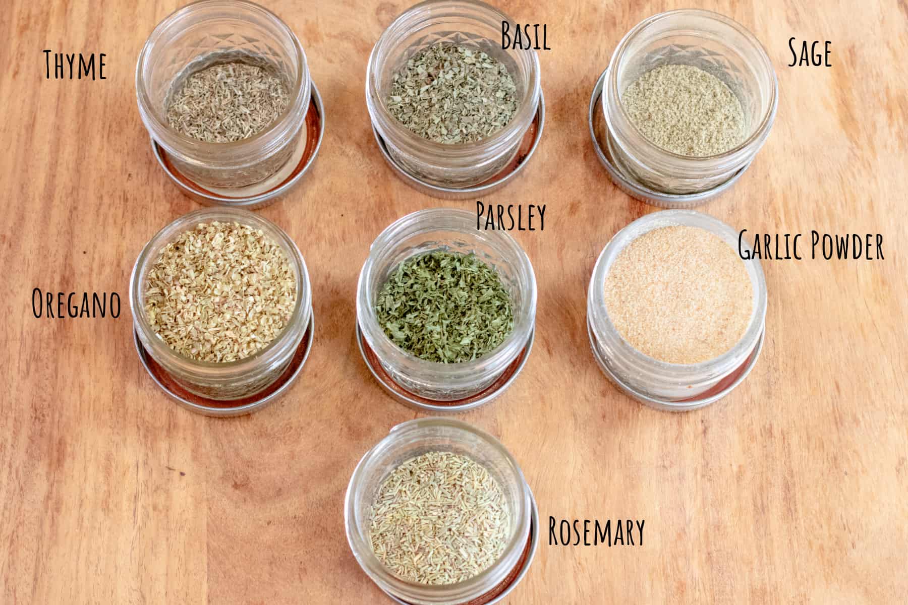 7 mason jars open with herbs and labeled.