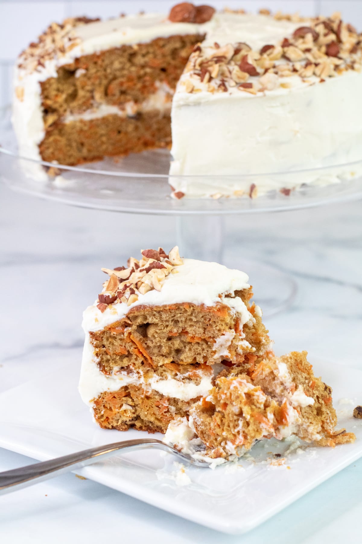 a plate with a slice of cake with a fork in it and in front of the whole cake with the piece take out. 