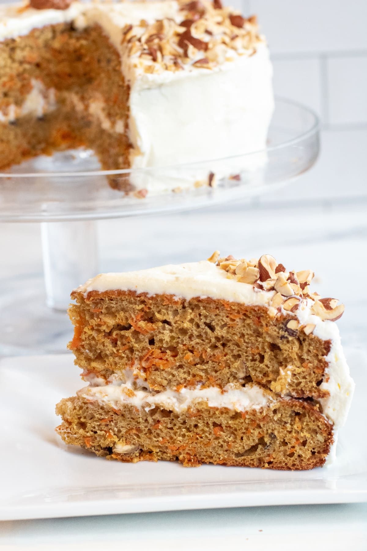 a slice of carrot cake on a plate next to a cut cake.