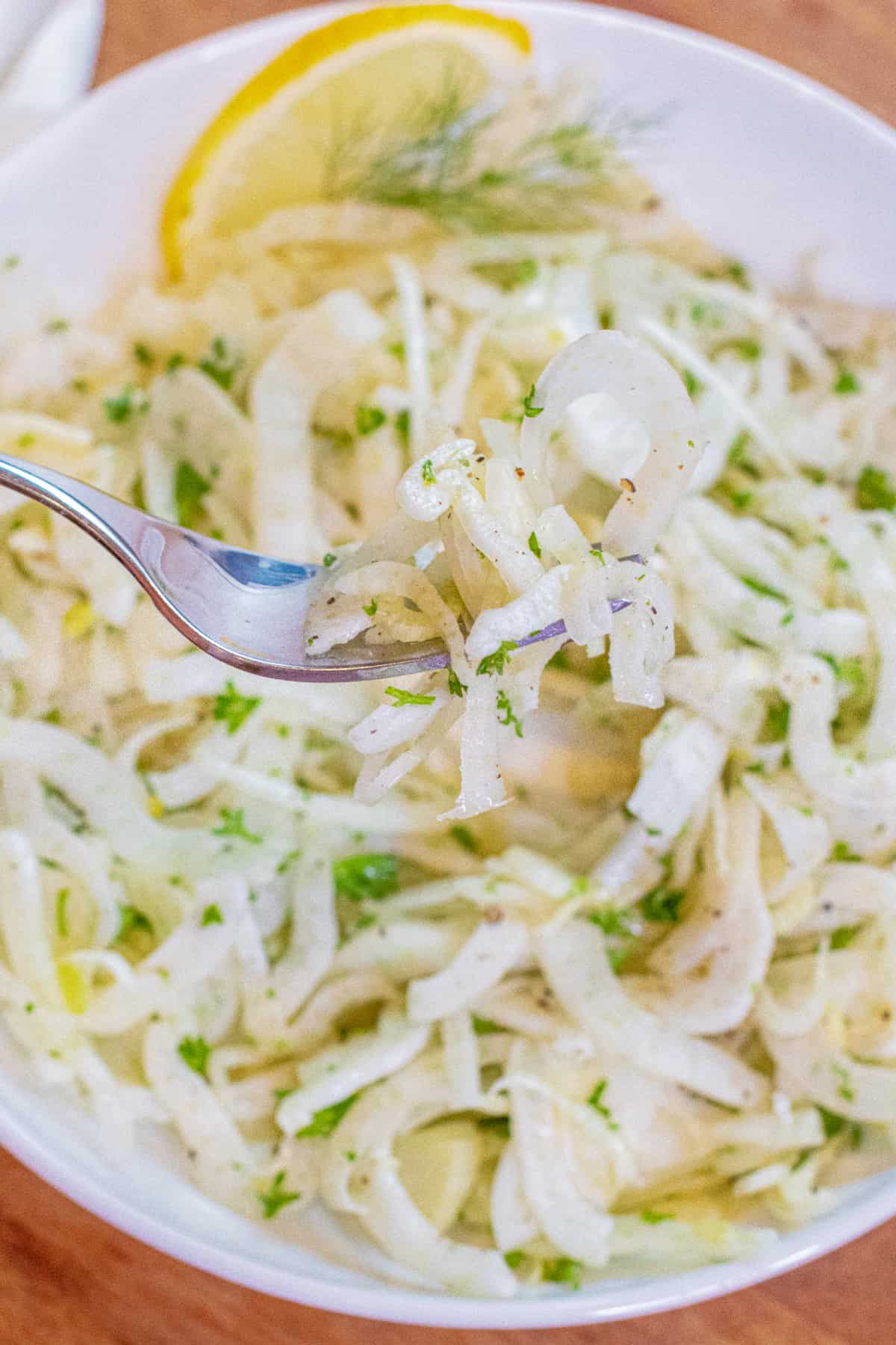 an overhead of a shaved fennel salad in a bowl with a fork.