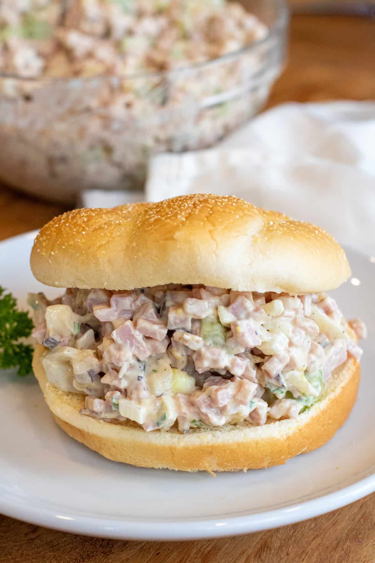 a ham salad in a bun on a plate.