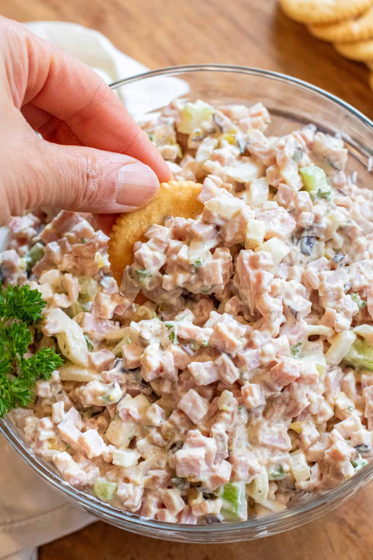 a hand with a ritz cracker scooping up some ham salad.