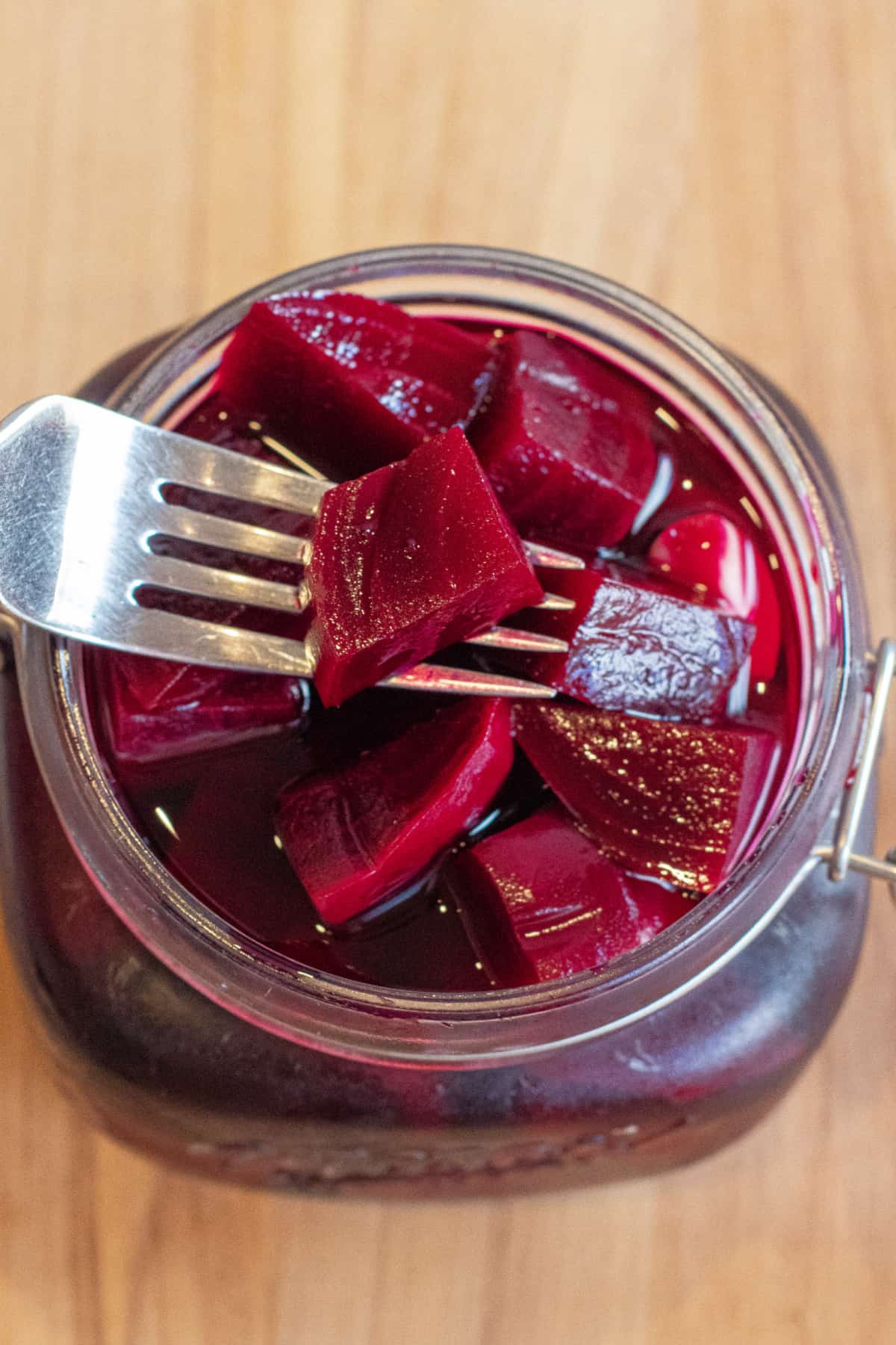 an open mason jar of pickled beets with a fork and a beet.