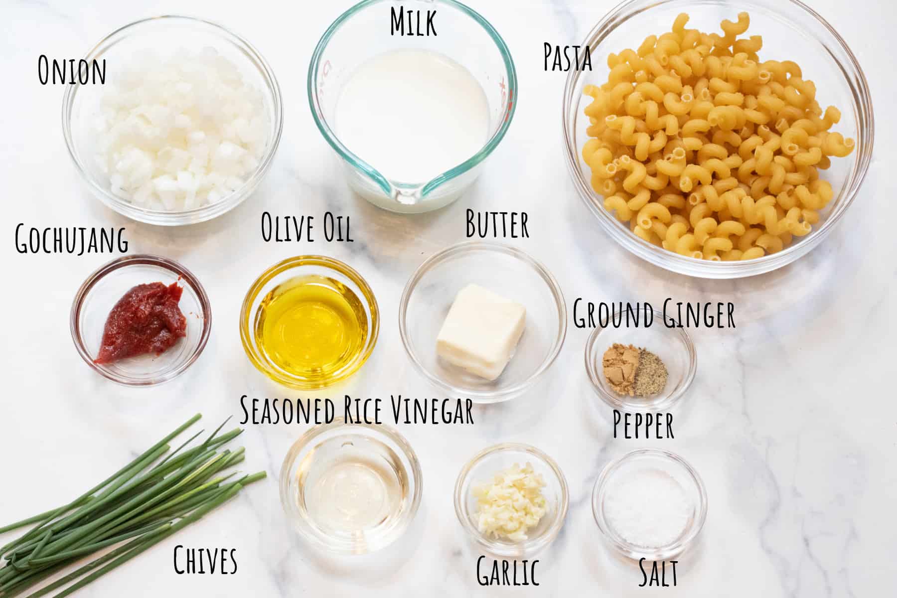 bowls of onion, pasta, milk, gochujang, oil, butter, spices, vinegar, garlic, salt, and chives labeled.