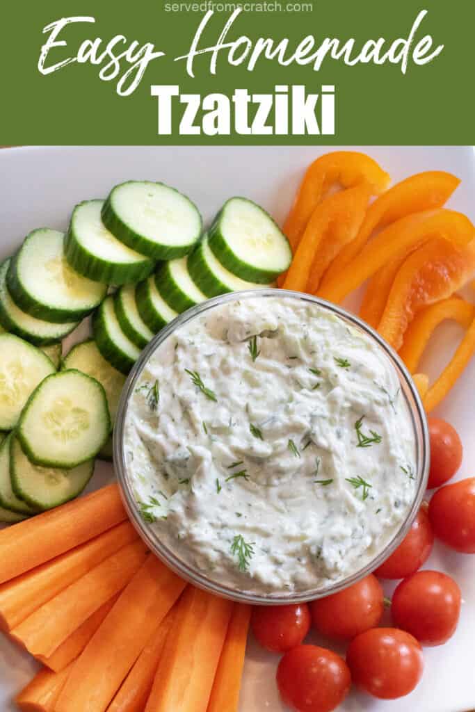 an overhead of a bowl of dill tzatziki surrounded by cucumbers, carrots, peppers, and tomatoes with Pinterest pin text.