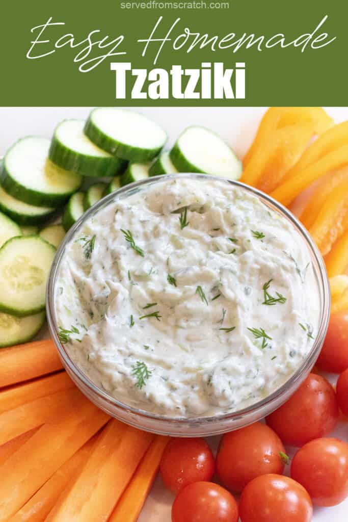 an overhead of a bowl of dill tzatziki surrounded by cucumbers, carrots, peppers, and tomatoes with Pinterest pin text.