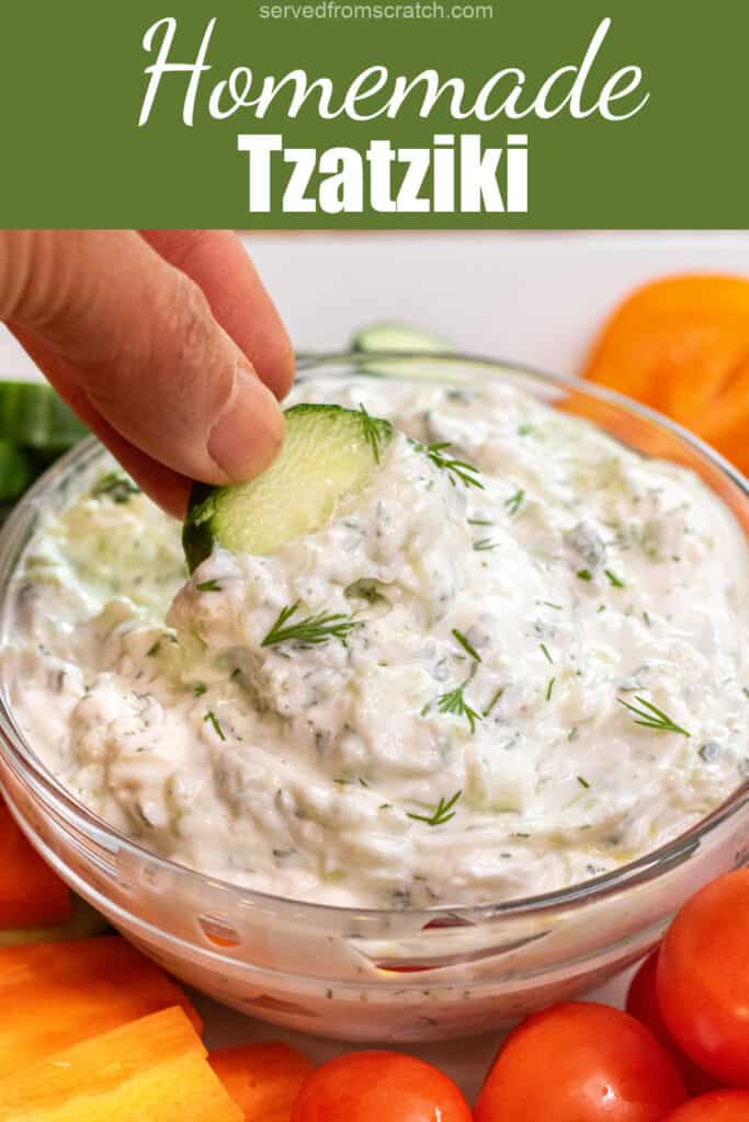 a hand holding a cucumber slice dipping into tzatziki in a bowl with Pinterest pin text.