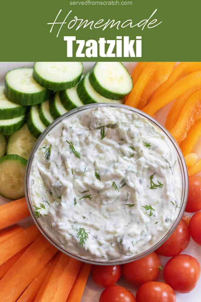 an overhead of a bowl of dill tzatziki surrounded by cucumbers, carrots, peppers, and tomatoes with Pinterest pin text.