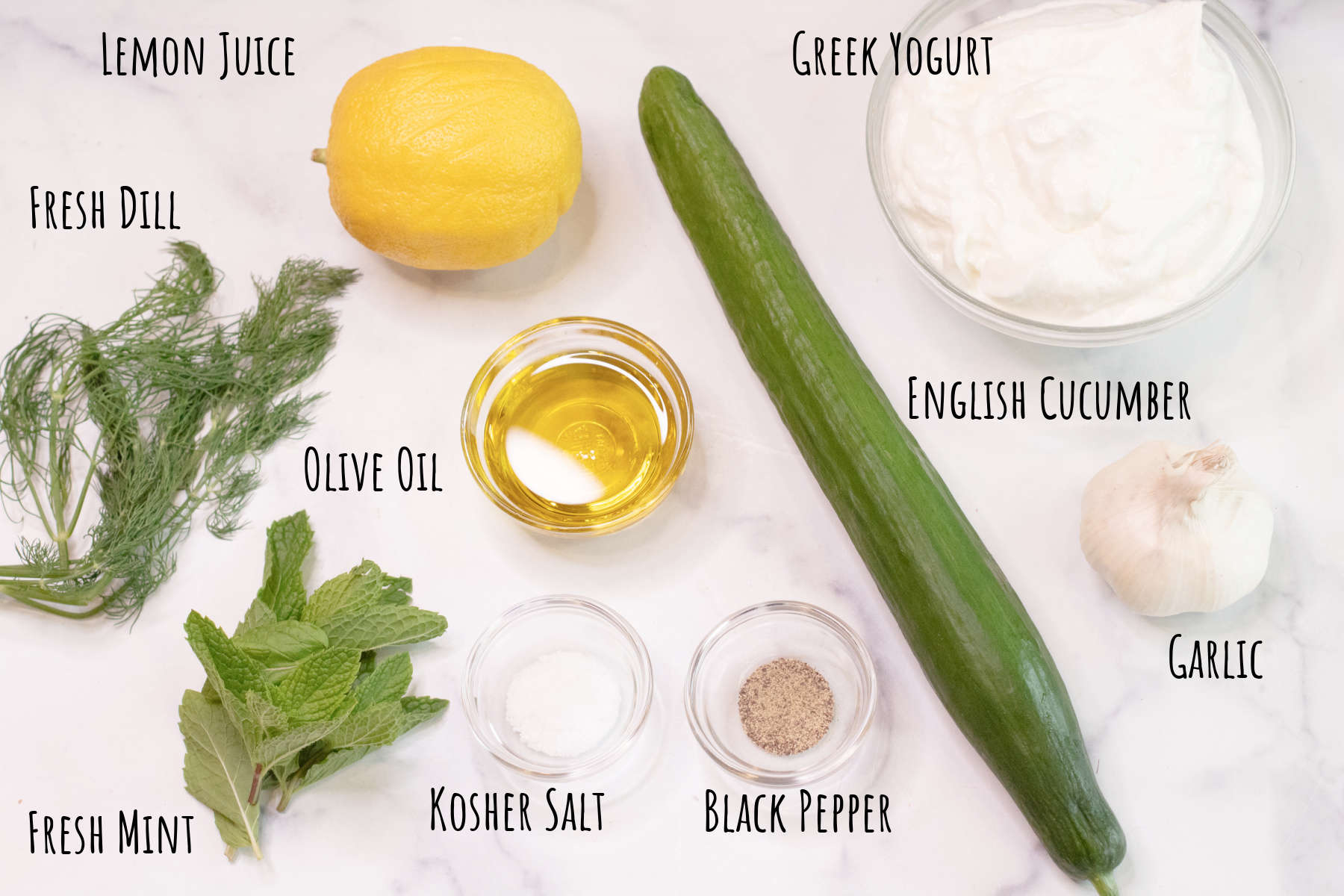 cucumber, yogurt, fresh dill, fresh mint, lemon, olive oil, garlic, salt and pepper labeled on counter.