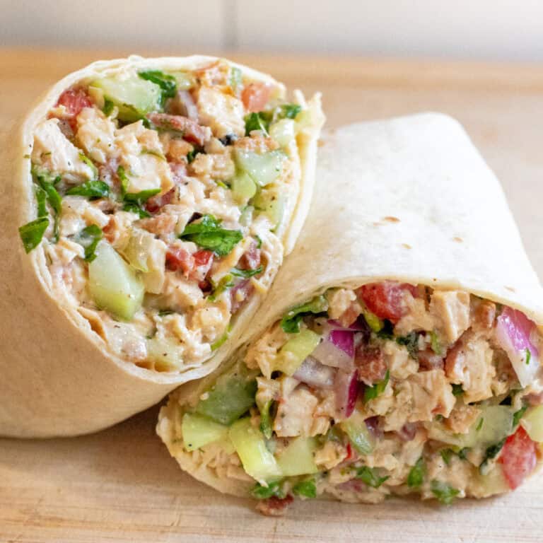 a halved sandwich wrap stuffed with greens and chicken and bacon.