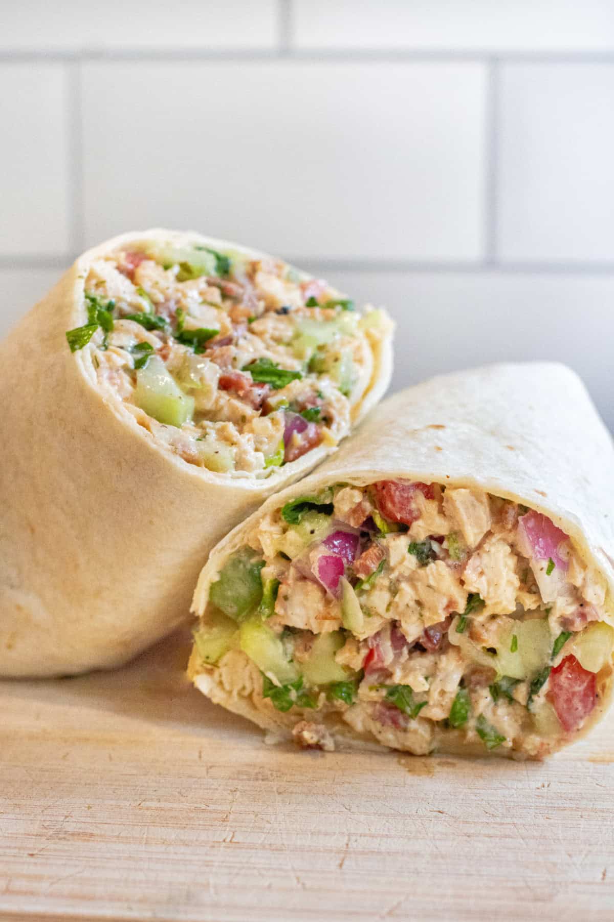 a halved sandwich wrap stuffed with greens and chicken and bacon.