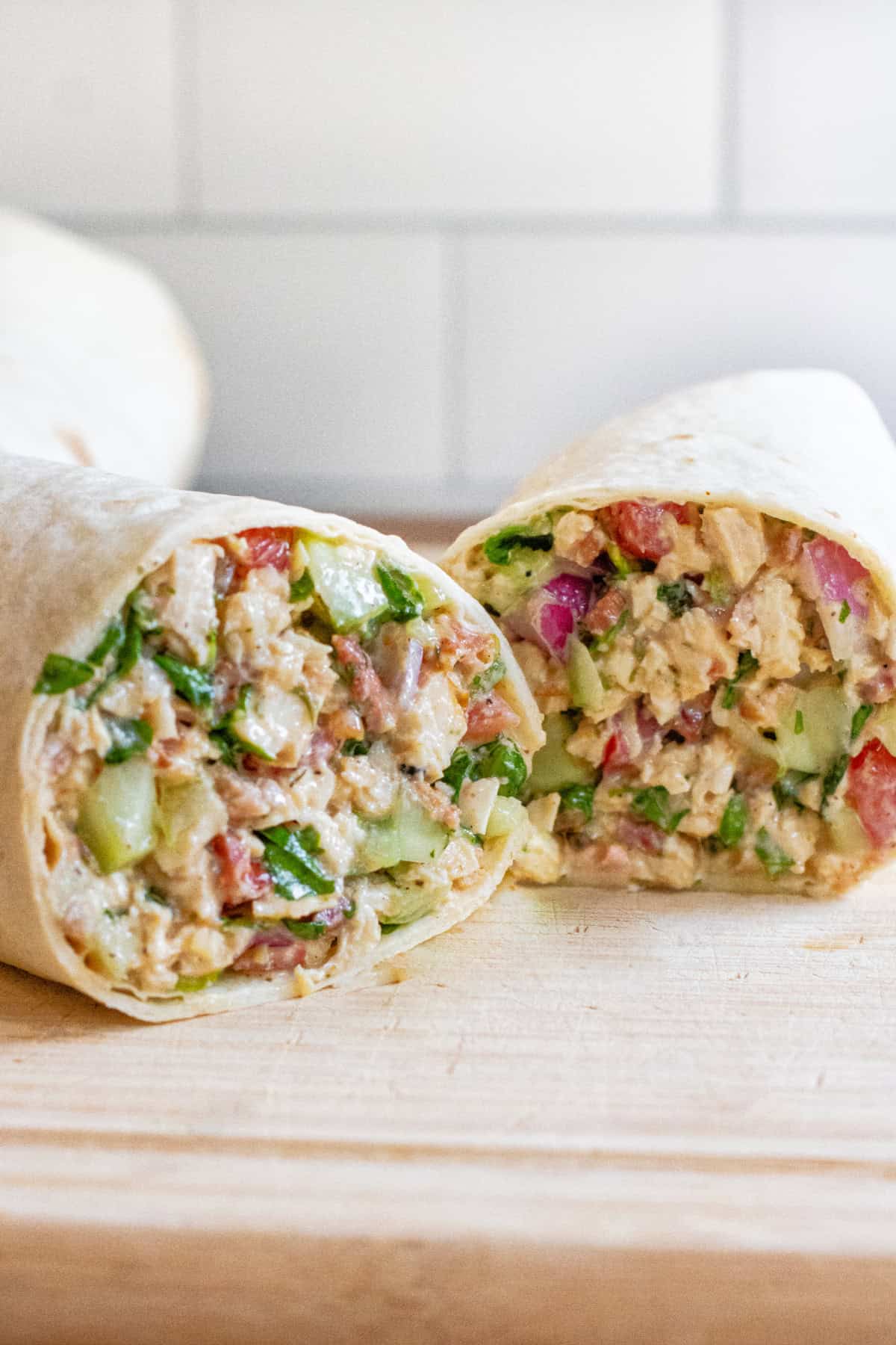 a halved sandwich wrap stuffed with greens and chicken and bacon.