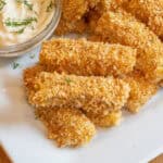 baked breaded fish sticks stacked on a plate.
