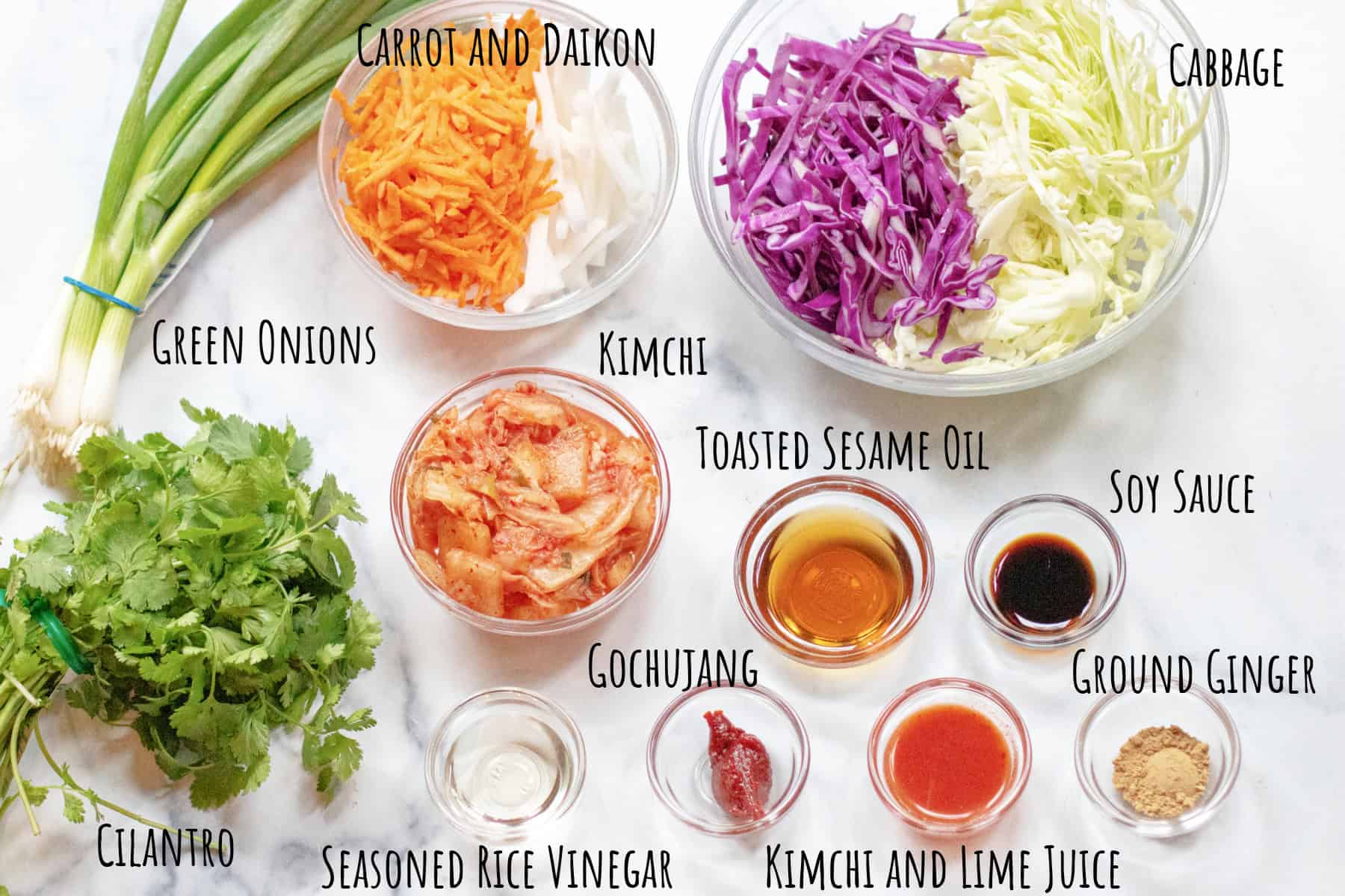 green onions, cilantro, bowls of cabbage, daikon and carrot, kimchi, oil, soy sauce, gochujang, and ginger labeled.