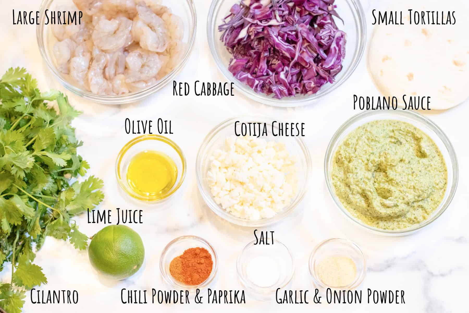 bowls of raw shrimp, cabbage, cotija cheese, poblano sauce, fresh cilantro, a lime, olive oil, spices all labeled.