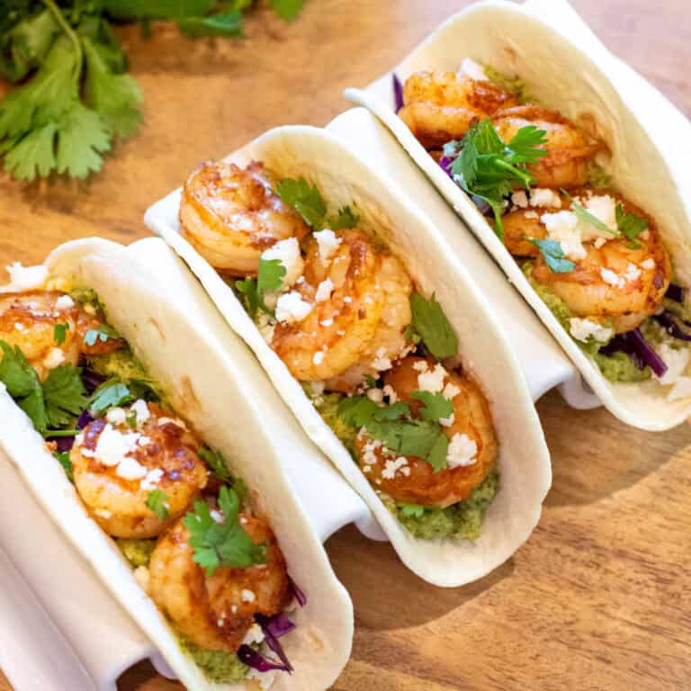 3 shrimp tacos in a holder.