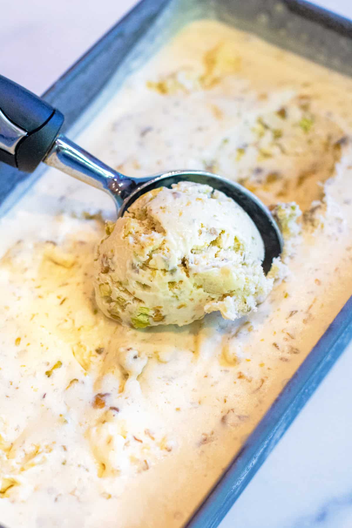 pistachio ice cream being scooped out of a loaf pan of ice cream.