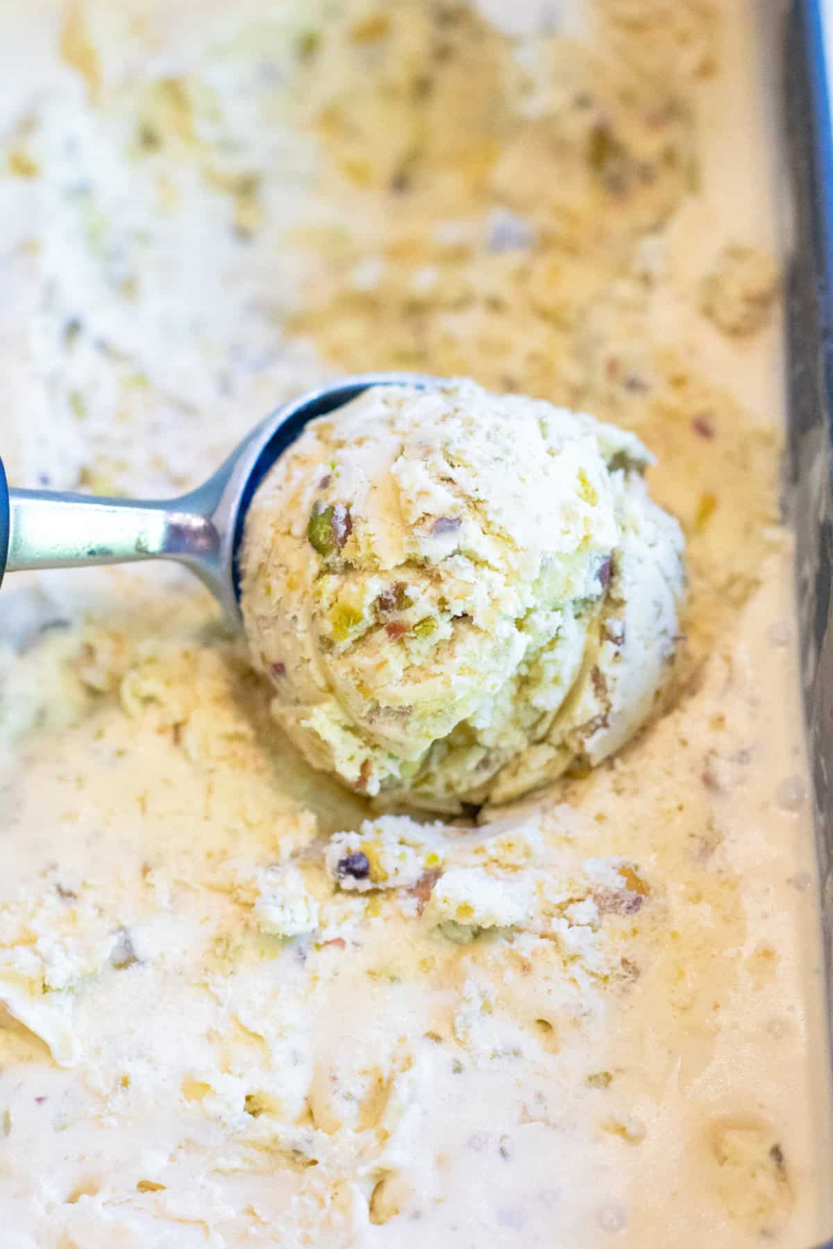 pistachio ice cream being scooped out of a loaf pan of ice cream.