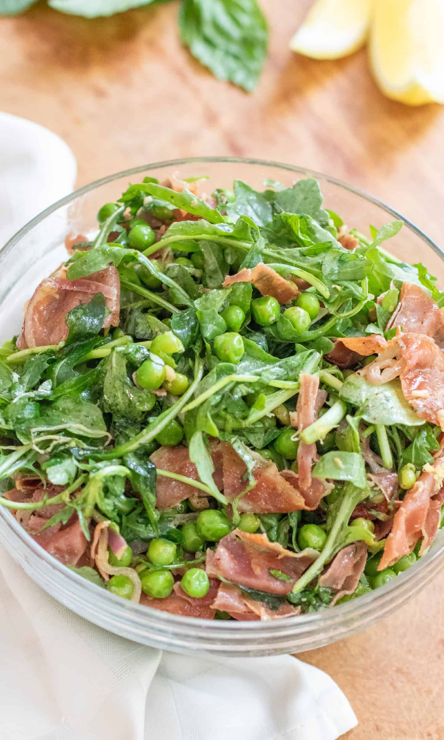a bowl of salad with peas, pancetta, and arugula.