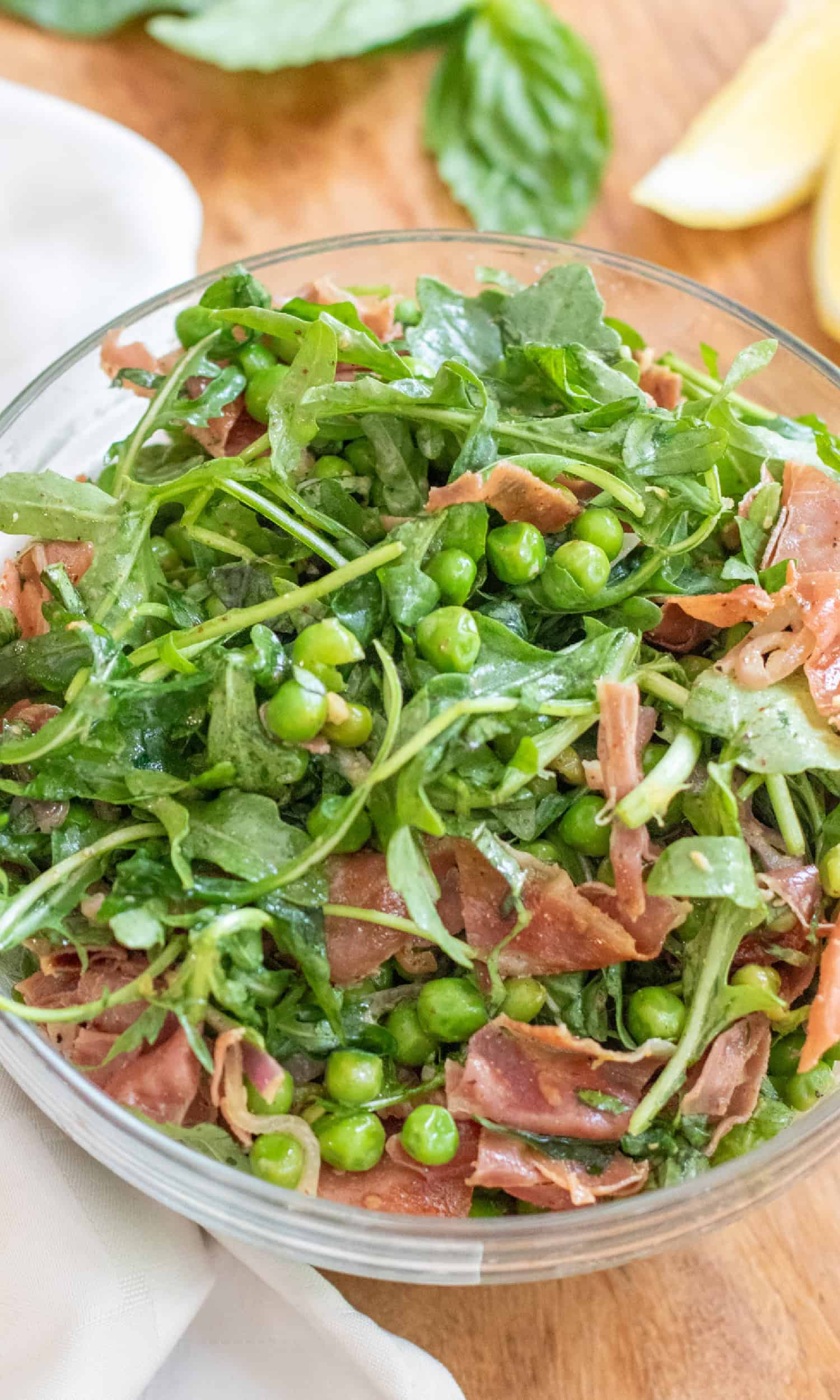 a bowl of salad with peas, pancetta, and arugula.