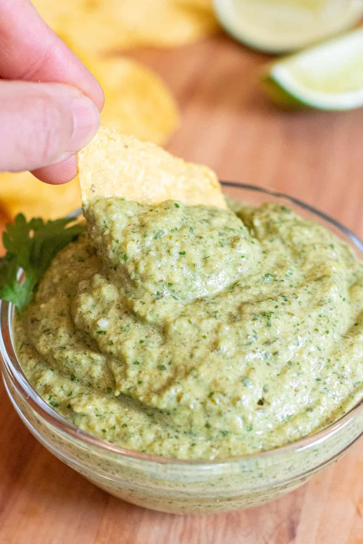 a bowl of poblano sauce with a chip being dipped in.