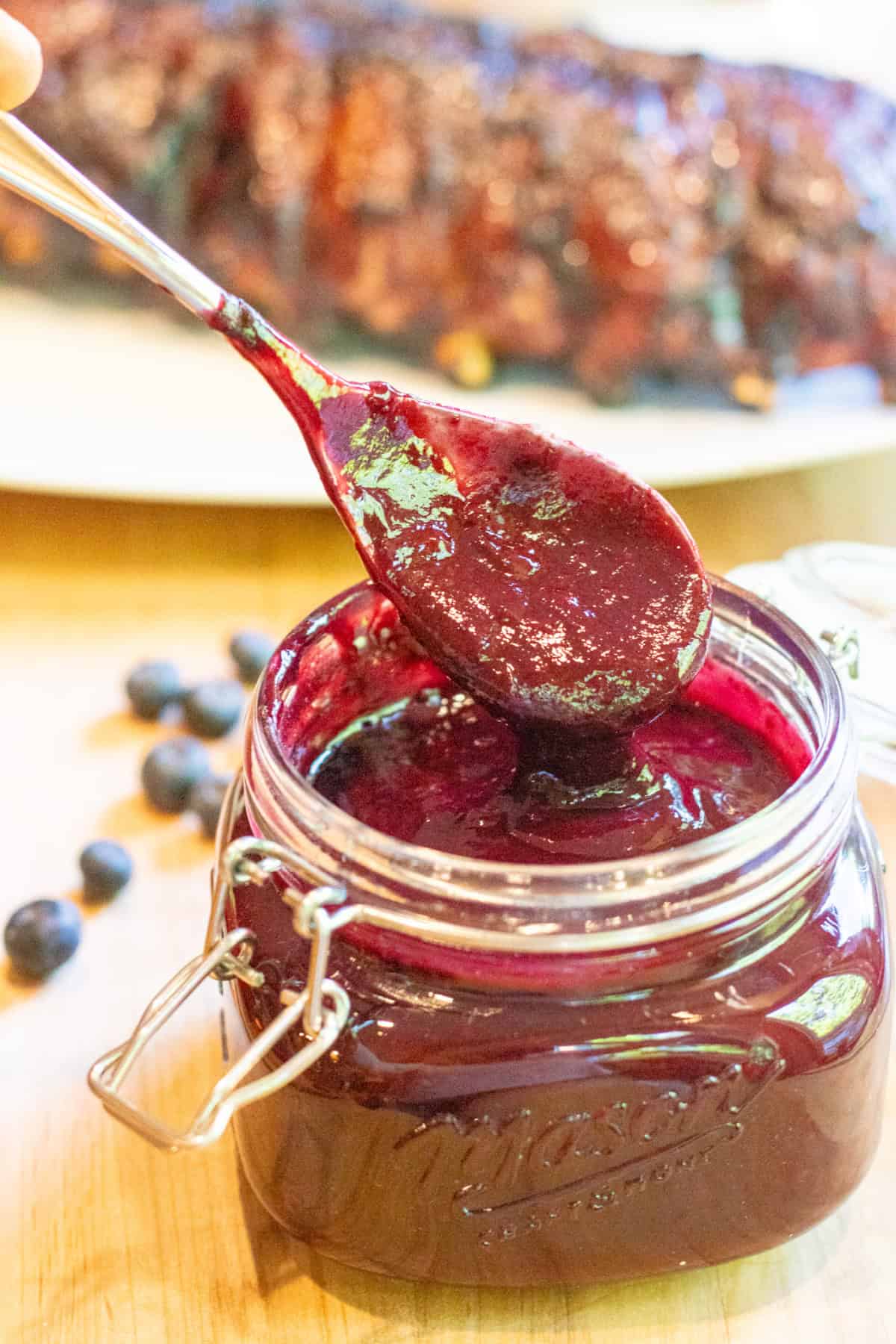 an open mason jar with a spoon and blueberry bbq sauce.