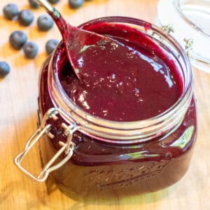 an open mason jar with a spoon and blueberry bbq sauce.