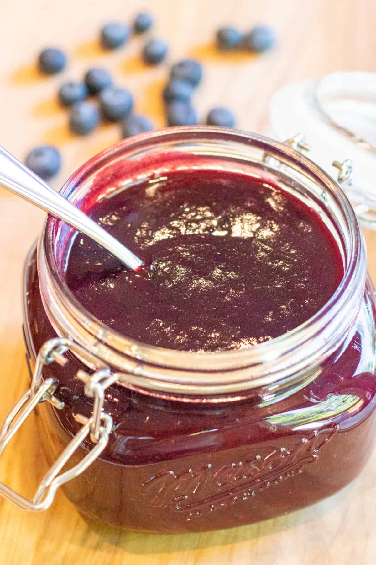 an open mason jar with a spoon and blueberry bbq sauce.
