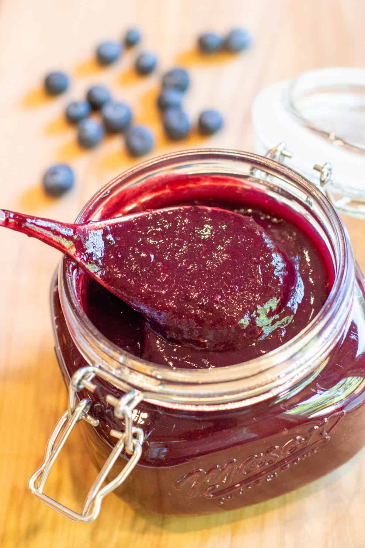 an open mason jar with a spoon and blueberry bbq sauce.