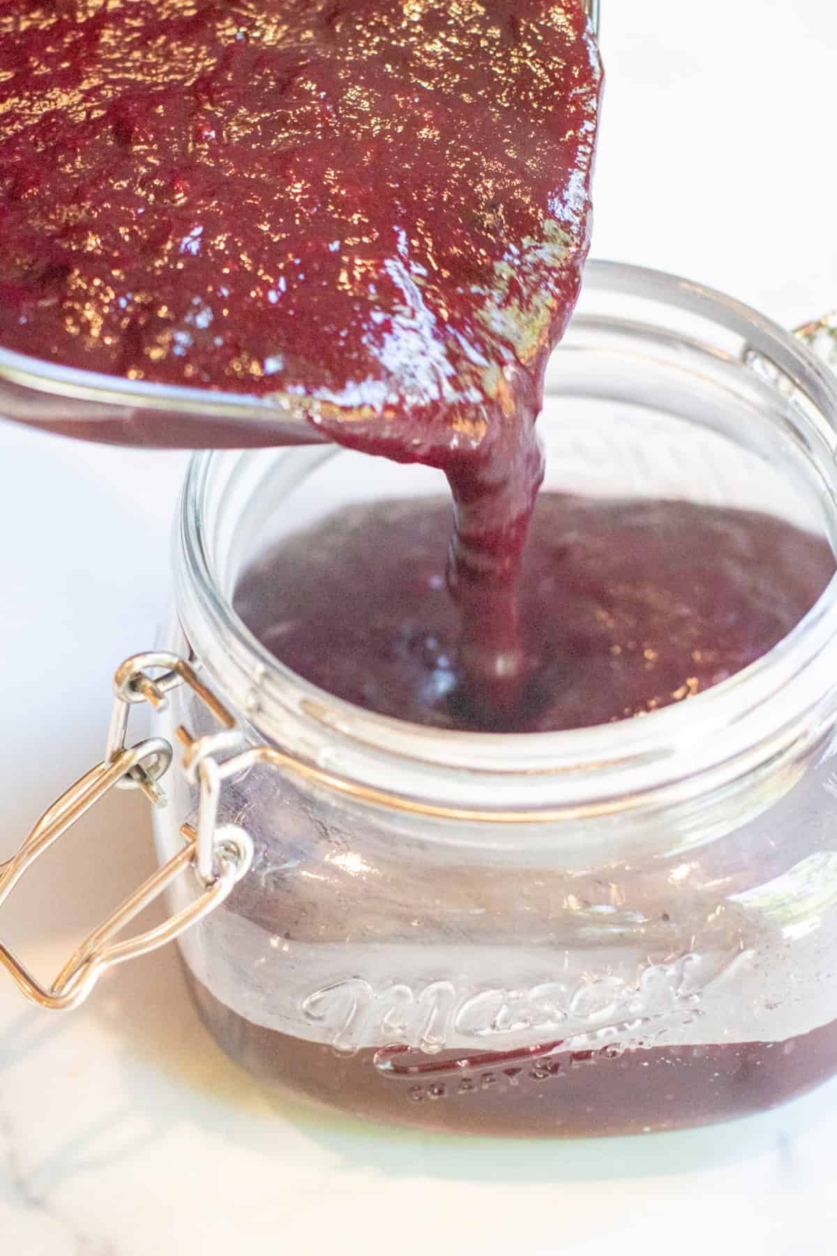 sauce being poured into a mason jar.