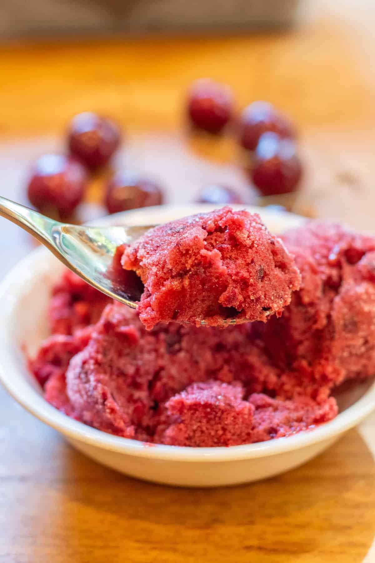 a bowl of 3 scoops of cherry sorbet with a spoonful.