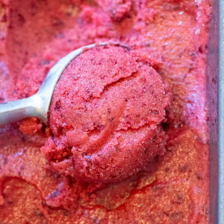 an ice cream scoop, scooping cherry sorbet from a loaf pan.