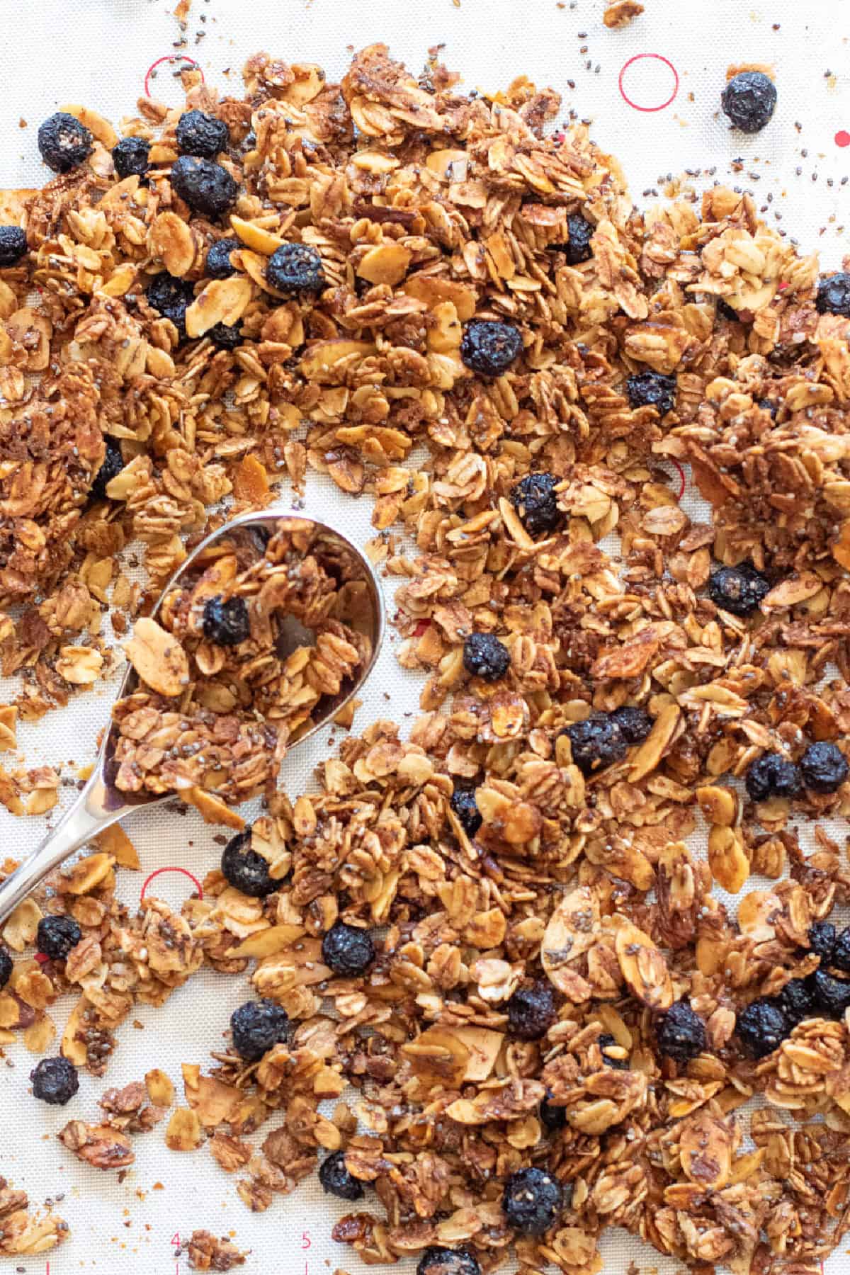 baked granola with dried blueberries on a tray with a spoon.