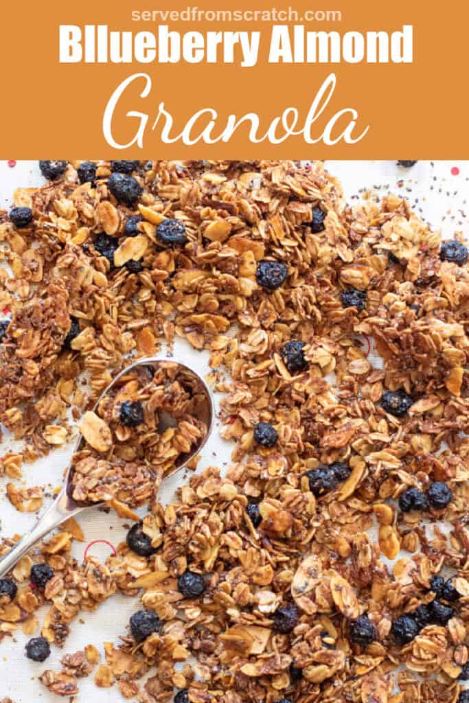 baked granola with dried blueberries on a tray with a spoon with Pinterest pin text.