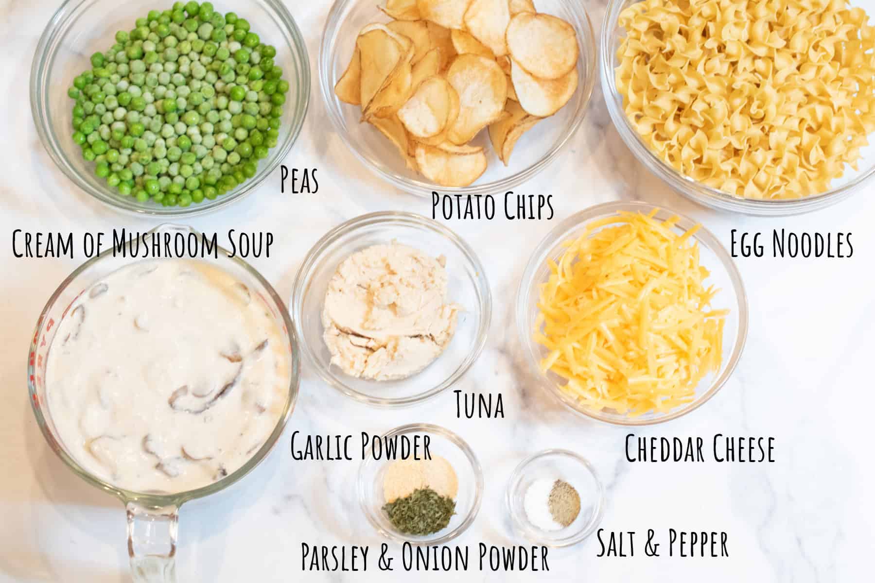 bowls of peas, potato chips, egg noodles, cream of mushroom soup, tuna, cheese, spices, all labeled.