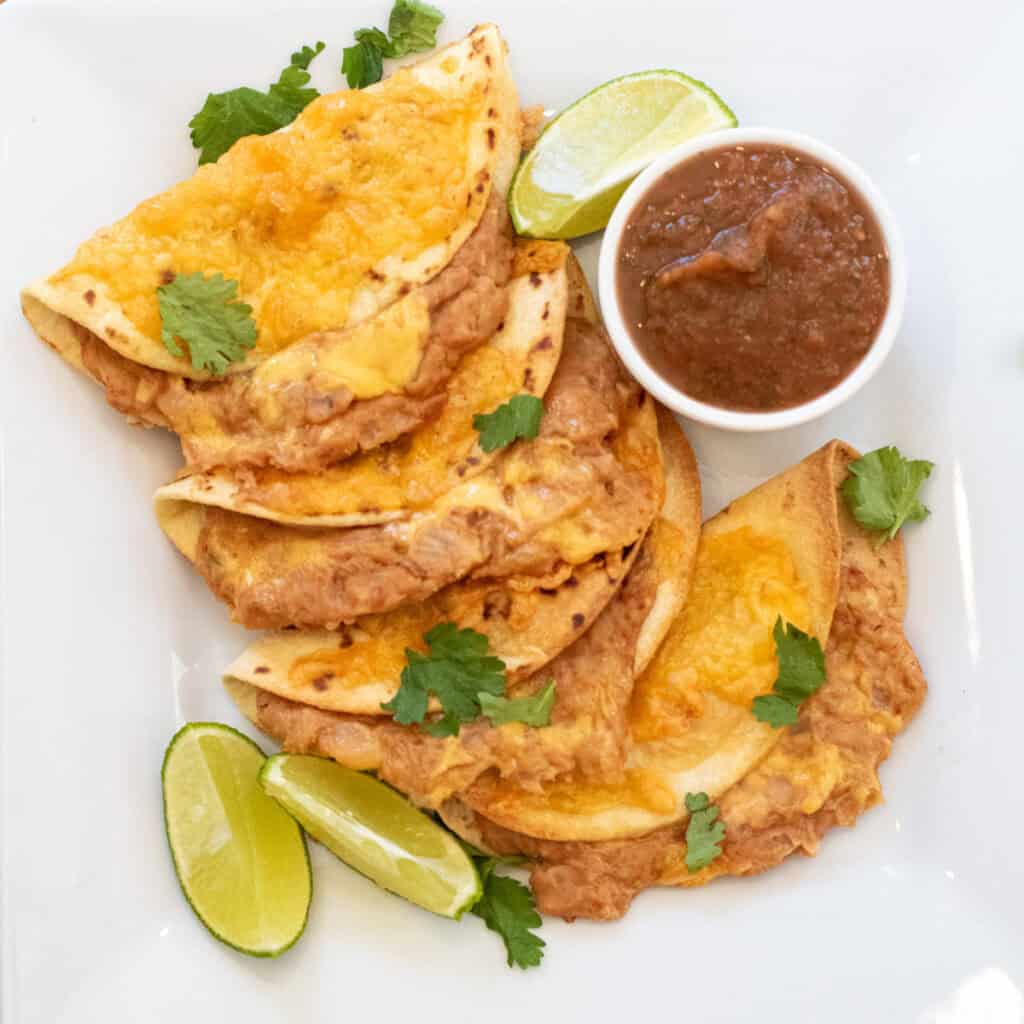 an overhead of a plate of crispy cheesy tacos stuffed with beans.