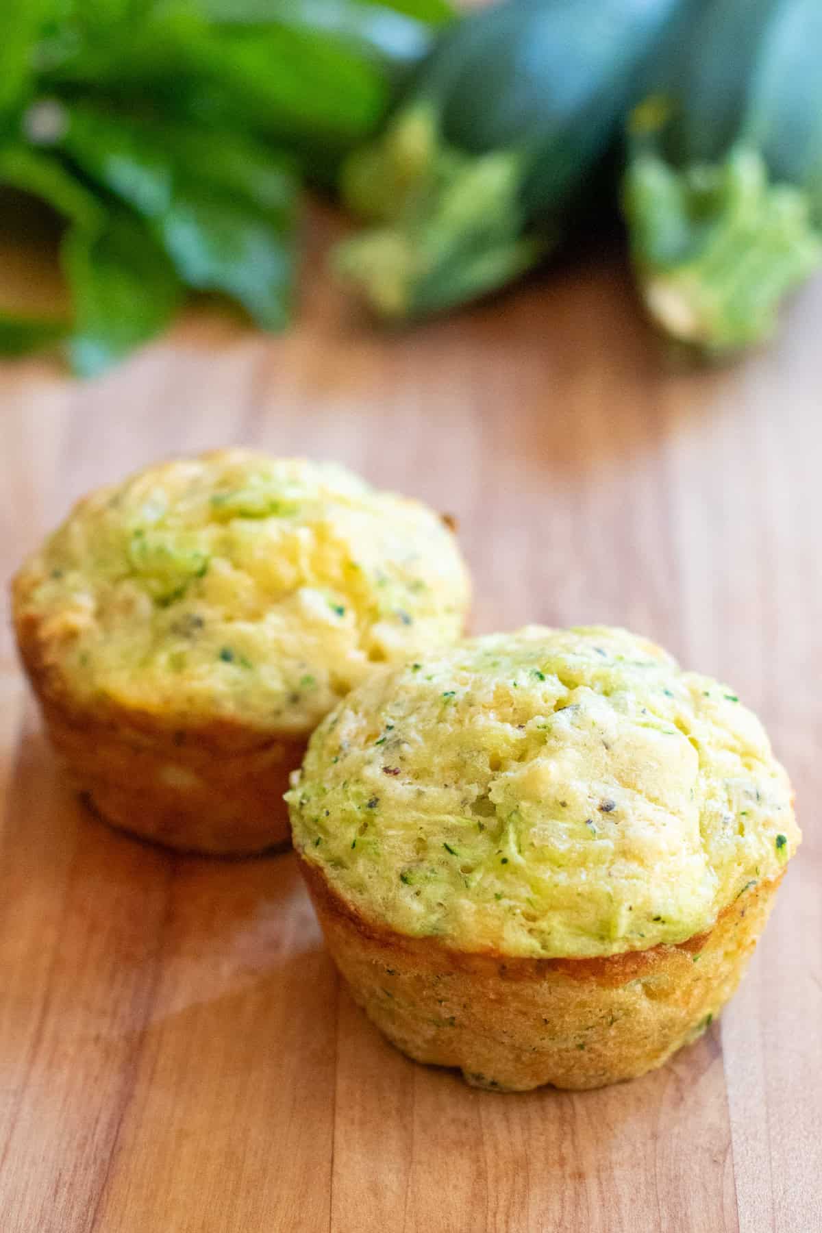 two zucchini muffins on a cutting board.