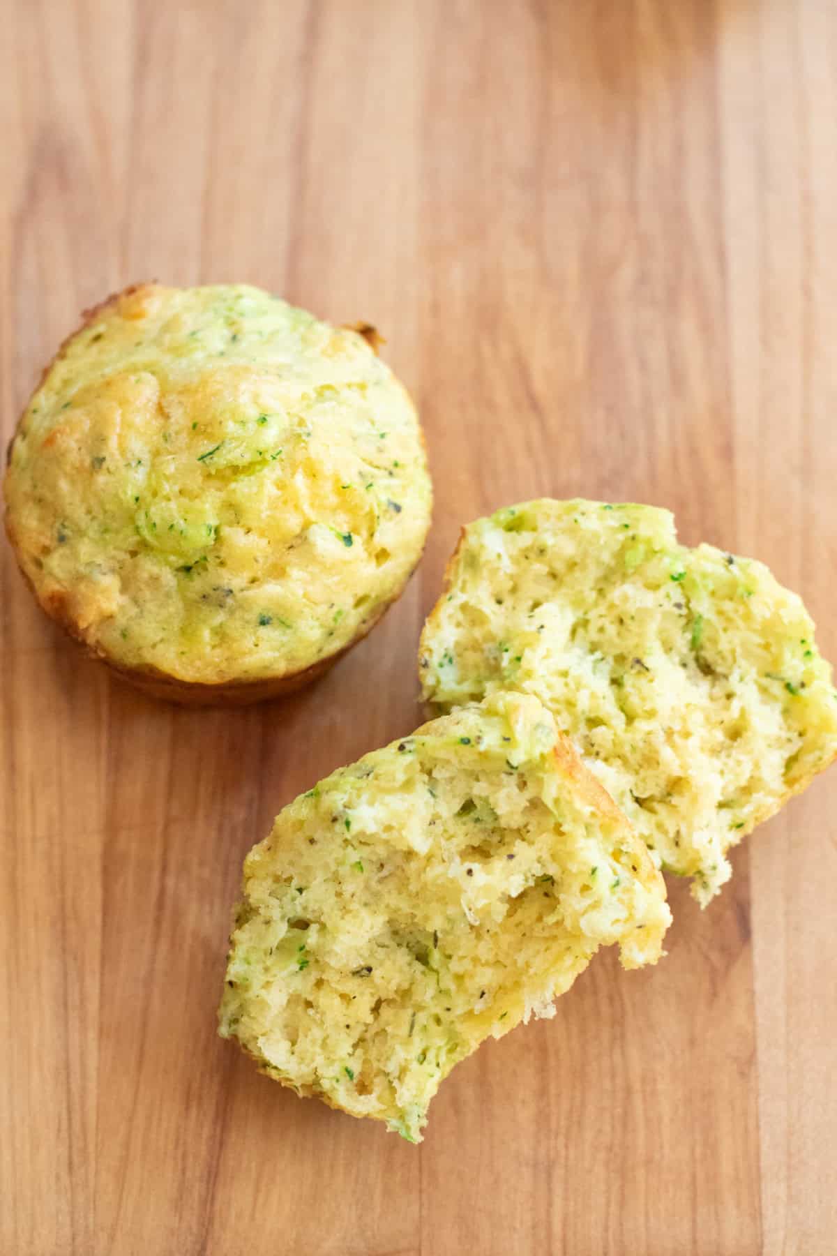 a muffin next to a halved muffin on a cutting board.