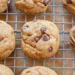 a round thick chocolate chip cookie on a cooling rack with other cookies.