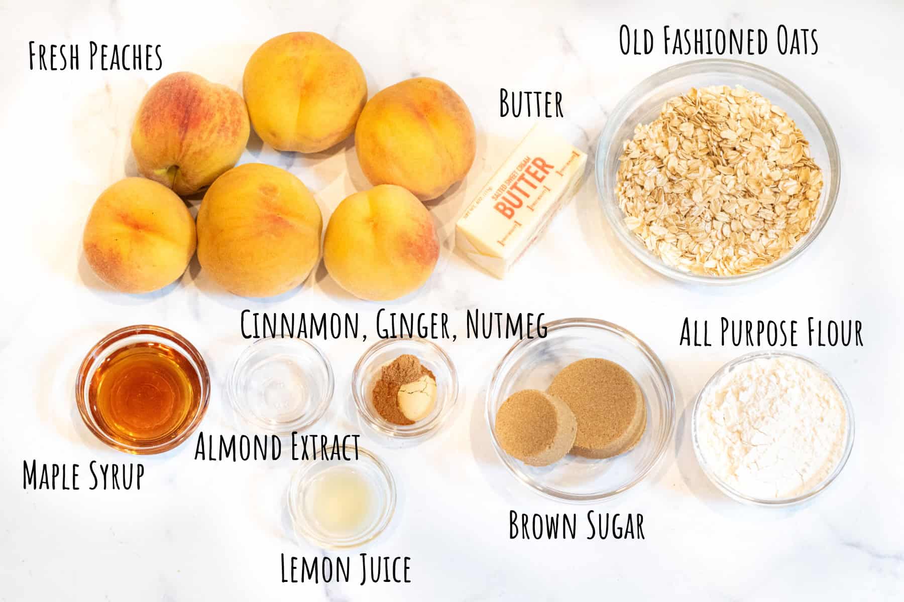 fresh peaches, a bowl of oats, butter, maple, flour, lemon juice, spices in bowls labeled.