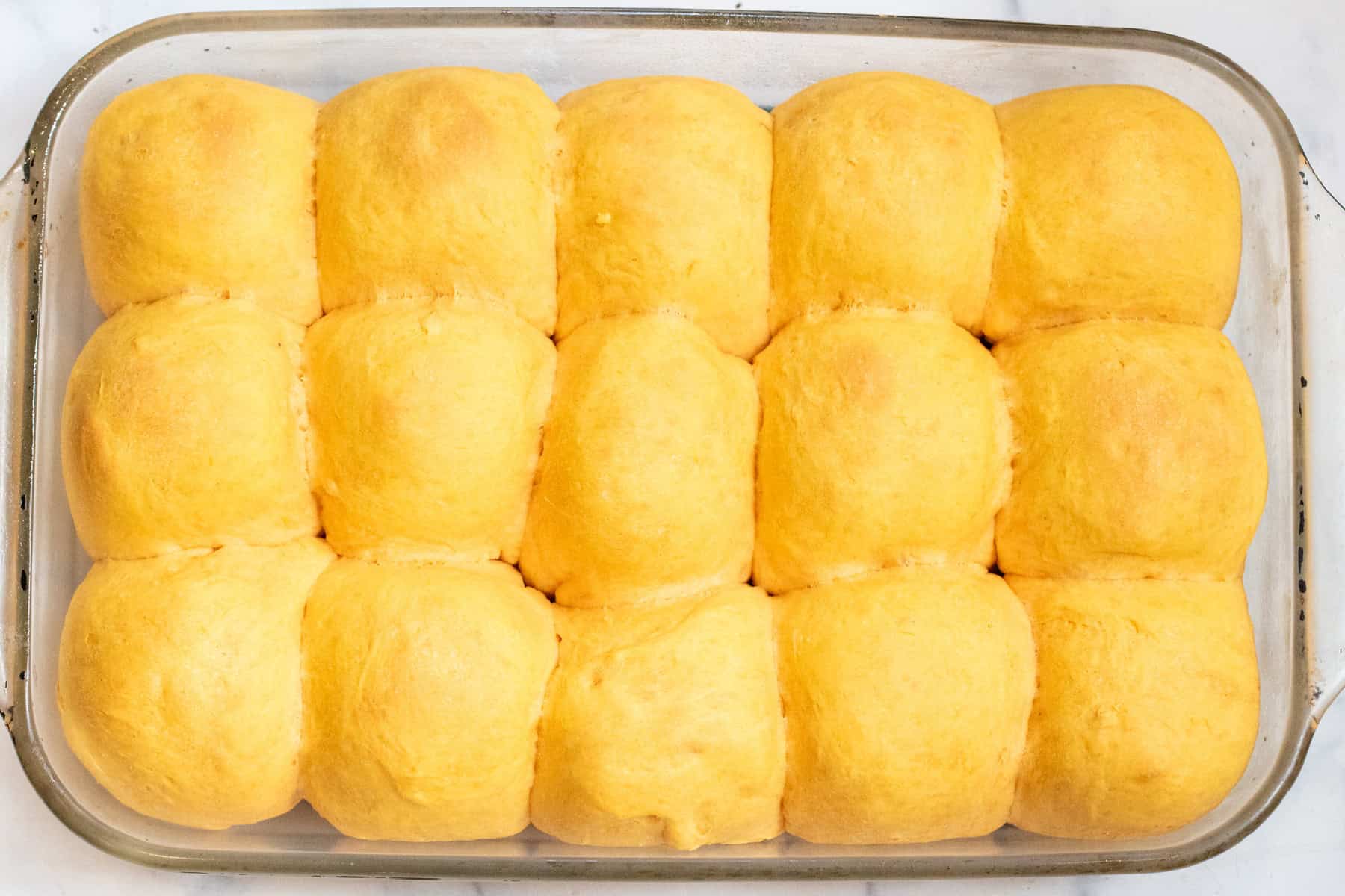 a glass baking dish with baked rolls. 