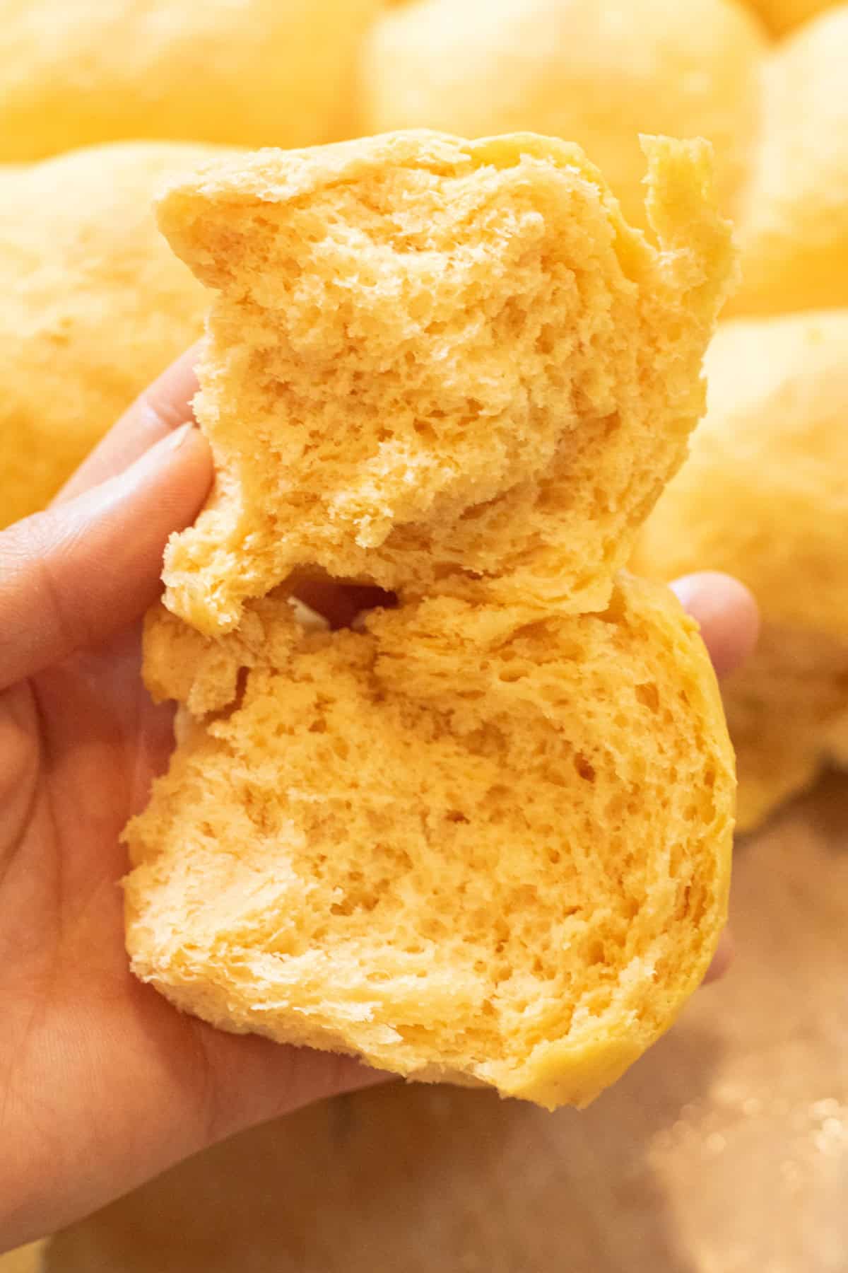 a hand holding a fluffy roll split in half.
