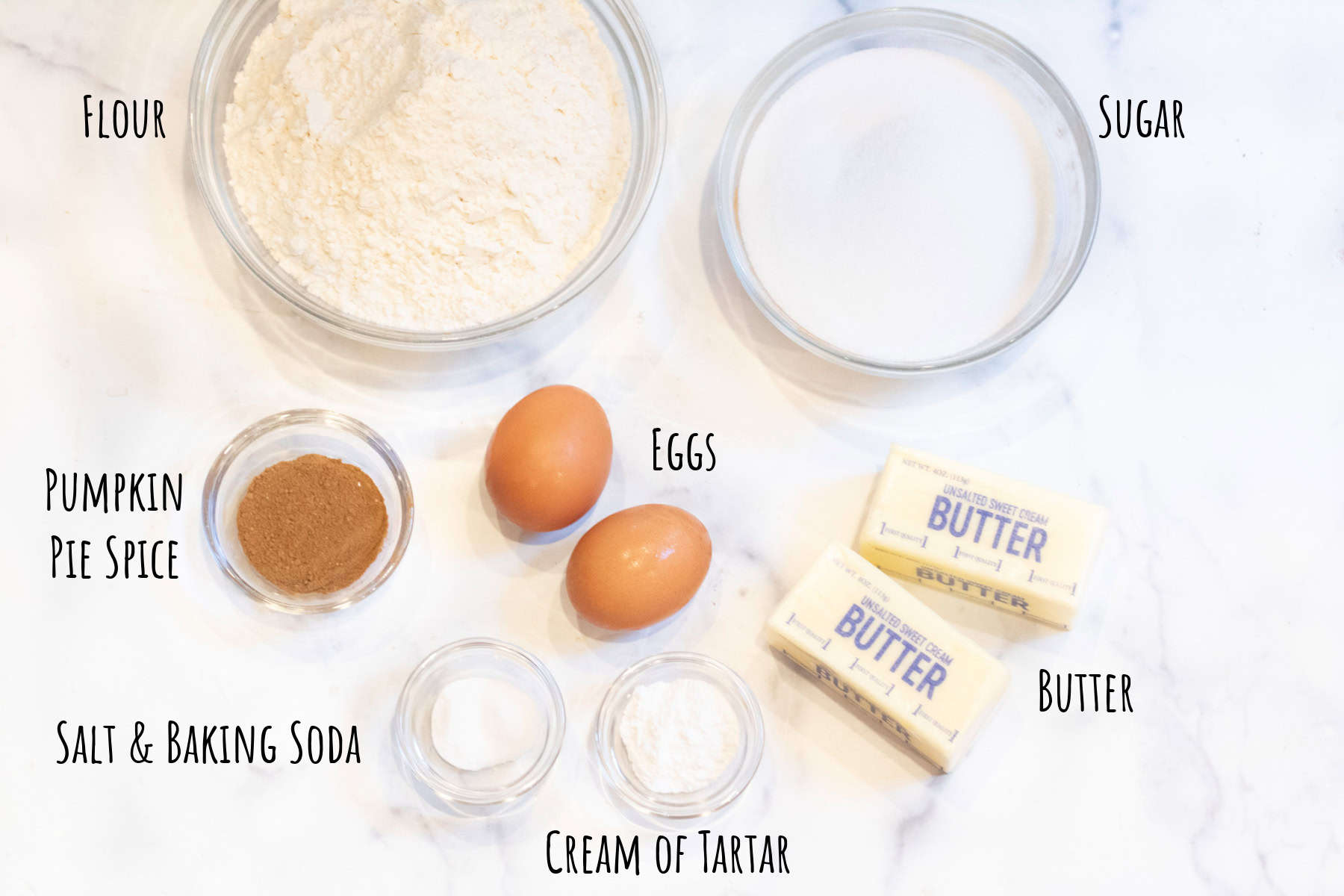 bowls of flour, sugar, pumpkin spice, eggs, butter, salt, and baking soda and cream of tartar labeled.