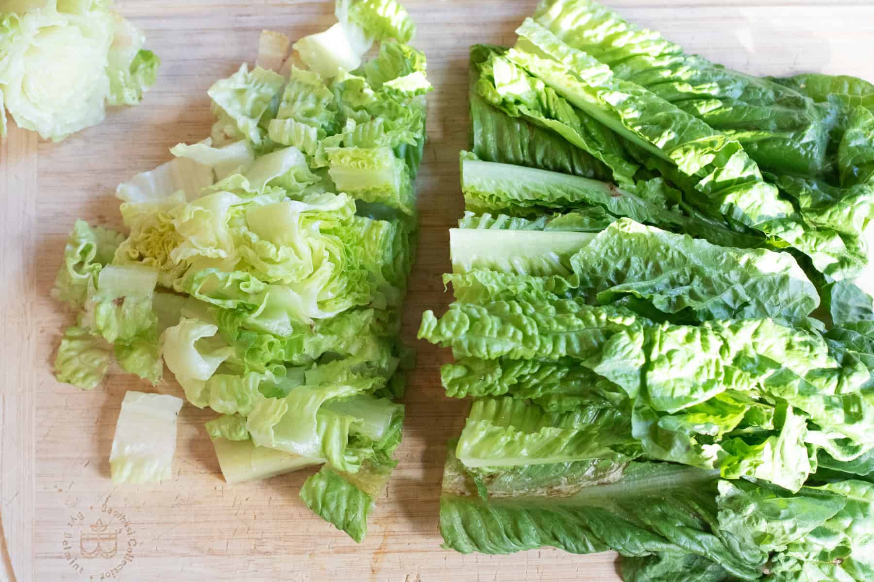 romaine lettuce on a cutting board being cut up.
