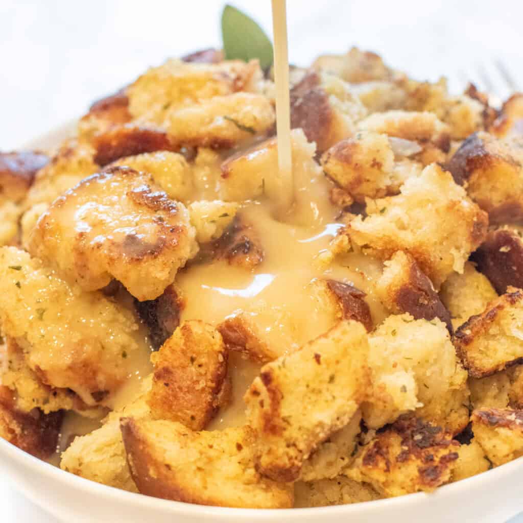 gravy being poured on a big bowl of bread dressing.